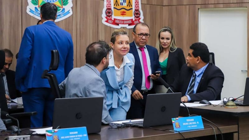 Plenário da Câmara Municipal de Várzea Grande durante sessão, com o brasão do município ao fundo