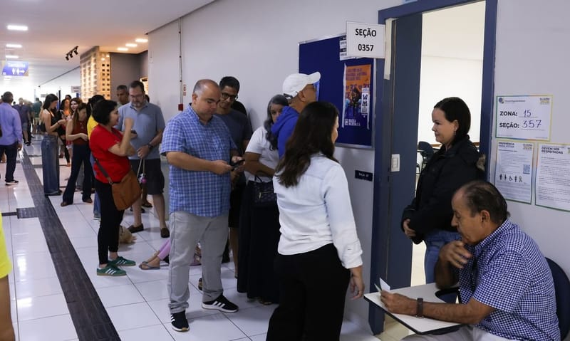Eleitores aguardam na porta de uma seção eleitoral identificada por placa com o número da seção, no primeiro turno em Brasília, 4 de outubro de 2026